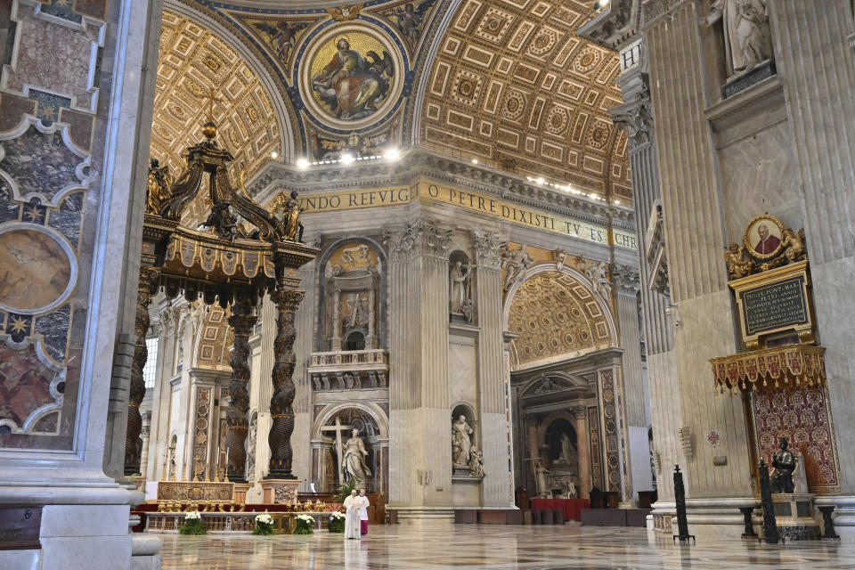 Pope Francis, small white figure at center left, delivers his blessing during Easter Sunday Mass inside an empty St. Peter's Basilica, at the Vatican, Sunday, April 12, 2020. Pope Francis and Christians around the world marked a solitary Easter Sunday, forced to celebrate the most joyful day in the liturgical calendar amid the sorrowful reminders of the devastation wrought by the coronavirus pandemic. The new coronavirus causes mild or moderate symptoms for most people, but for some, especially older adults and people with existing health problems, it can cause more severe illness or death. (Andreas Solaro/Pool Photo via AP)