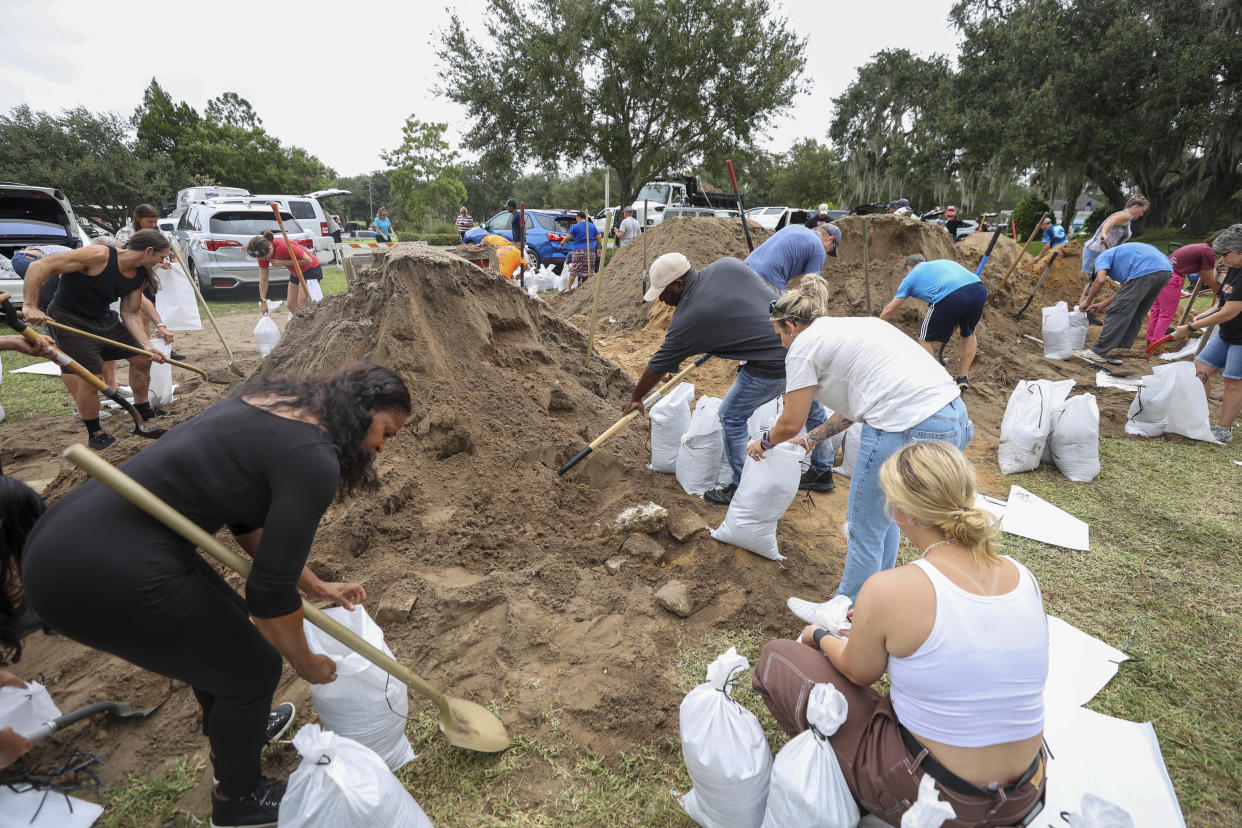 Residents and city workers fill sandbags at West Park in downtown Clermont, Fla., Tuesday, Sept. 27, 2022, in preparation for Hurricane Ian. (Rich Pope/Orlando Sentinel via AP)