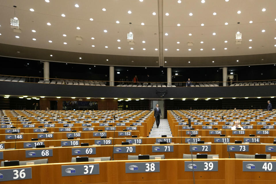 A man walks past desks during a plenary session in the European Parliament in Brussels, Wednesday, March 29, 2023. (AP Photo/Virginia Mayo)