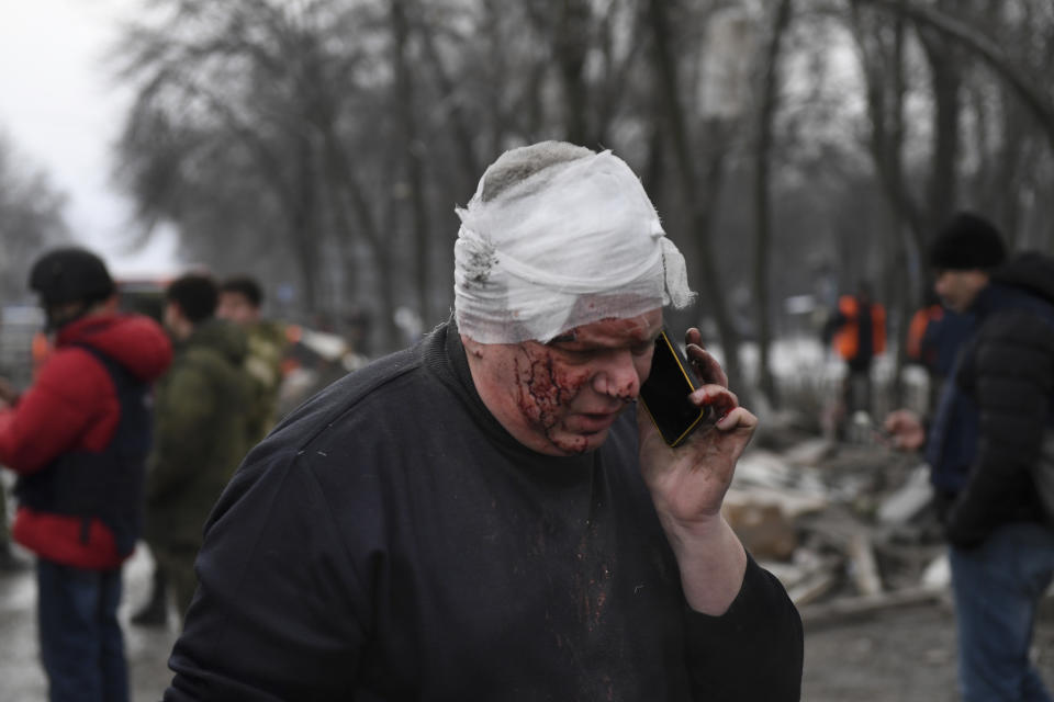 A wounded man speaks on the phone as Donetsk's emergency employees work at a site of a shopping center destroyed after what Russian officials in Donetsk said it was a shelling by Ukrainian forces, in Donetsk, in Russian-controlled Donetsk region, eastern Ukraine, Monday, Jan. 16, 2023. (AP Photo)