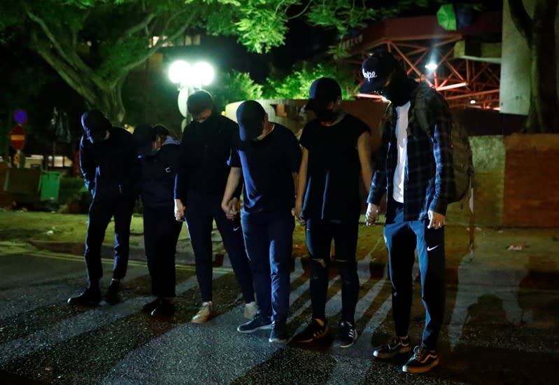 Anti-government protesters wait to give themselves up to the police as they leave the campus of the Polytechnic University (PolyU) in Hong Kong