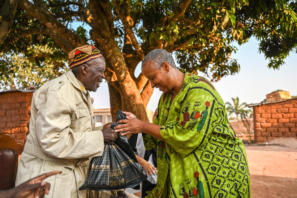 Wanda Tucker presents a bottle of wine to a village soba, Antonio Manuel Domingos, in Kalandula. A soba is a leader who inherits the position by birth, through the mother's side. Taking a gift when meeting a soba is expected. It is a sign of respect.