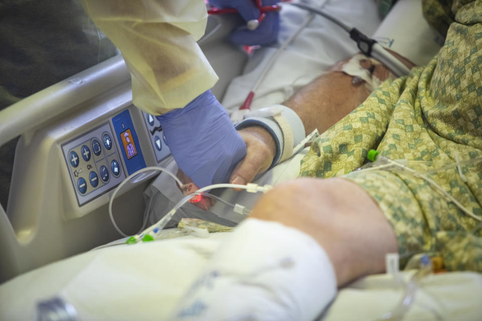 Dr. William Dittrich M.D. holds the hand of a COVID-19 patient in the Medical Intensive care unit (MICU) at St. Luke's Boise Medical Center in Boise, Idaho on Tuesday, Aug. 31, 2021. More then half of the patients in the ICU are COVID-19 positive, none of which are vaccinated. (AP Photo/Kyle Green)