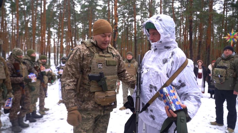 Lieutenant-General Serhii Naiev, left, stands with a Ukrainian soldier, with others behind them, in a snowy woodland in northern Ukraine on December 25, 2023.
