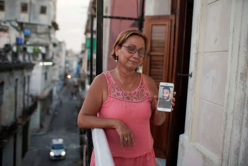 Raisa González reacciona mientras muestra una foto de su hijo Angelo Troya González, un artista sancionado tras las protestas, en La Habana, Cuba.