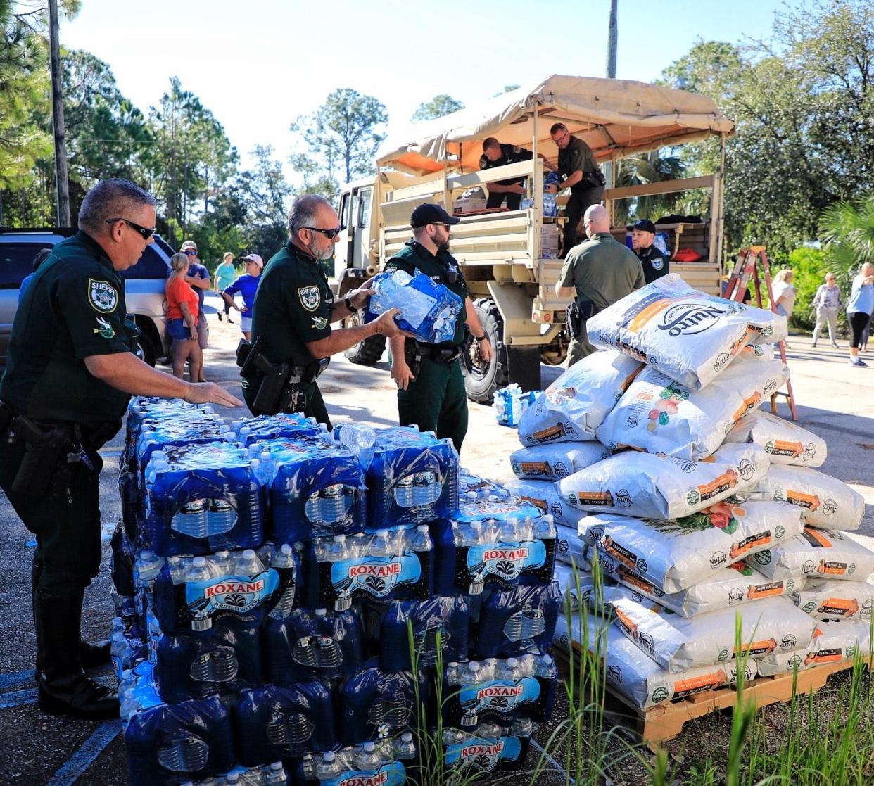 Members of the Volusia Sheriff's Office offload cases of water and bags of pet food from a truck Wednesday for Lake Harney Woods residents still dealing with flooding after Ian.