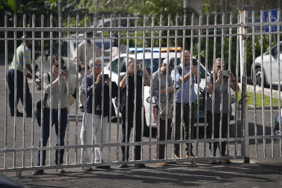 Reporters film through a gate as they await the arrival of FTX founder Sam Bankman-Fried, at the Magistrate Court building in Nassau, Bahamas, Wednesday, Dec. 21, 2022.(AP Photo/Rebecca Blackwell)