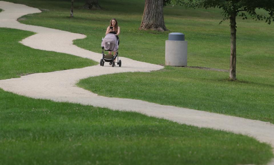 Martina Stojanovska pushes her daughter in a stroller along the new Schneider Park walking path Monday in West Akron.