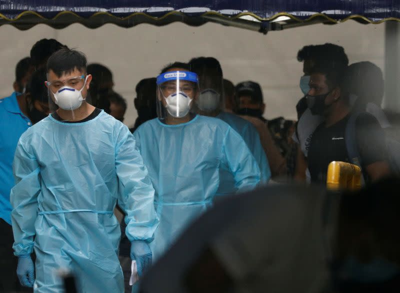 Personnel in protective garment usher a group of migrant workers at Westlite Woodlands dormitory in Singapore