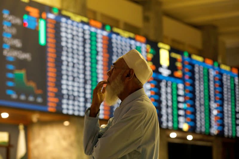 Stock broker monitors the market on the electronic board displaying share prices at the Pakistan Stock Exchange, in Karachi