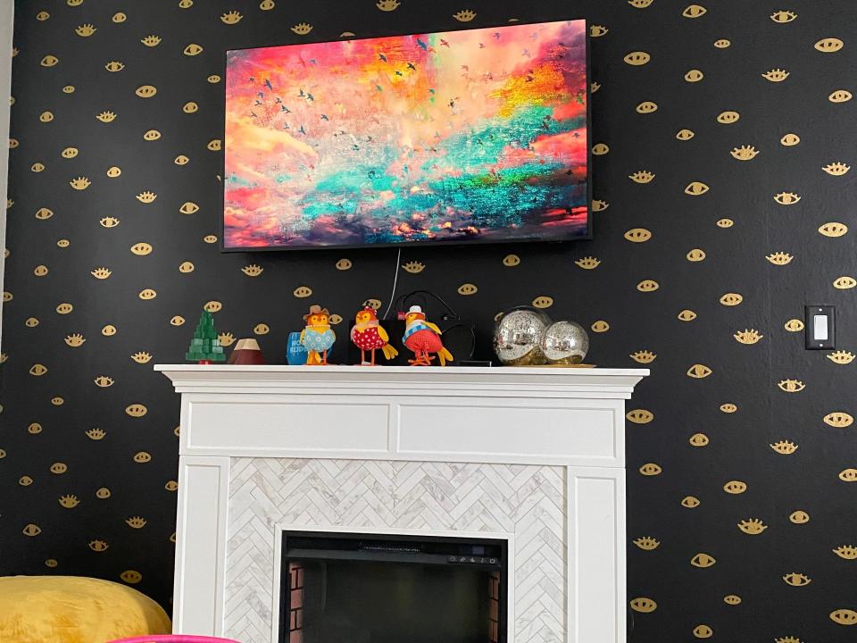 Interior view of mobile home living room with black-and-gold wallpaper, white fireplace, and tv