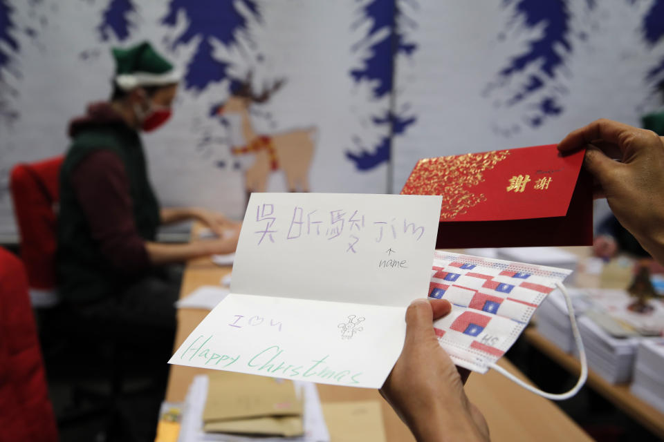 A postal worker shows an envelope from Jim of Taiwan, who sent a face mask inside the letter he sent and wrote "I (heart) U," in Libourne, southwest France, Monday, Nov. 23, 2020. Letters pouring by the tens of thousands into Santa's mailbox offer a glimpse into the worries and hopes of children awaiting a pandemic-hit Christmas. Along with usual pleas for toys and gadgets, kids are also mailing requests for vaccines, for visits from grandparents, for life to return to the way it was. The office estimates that one letter in three mentions the pandemic. (AP Photo/Francois Mori)