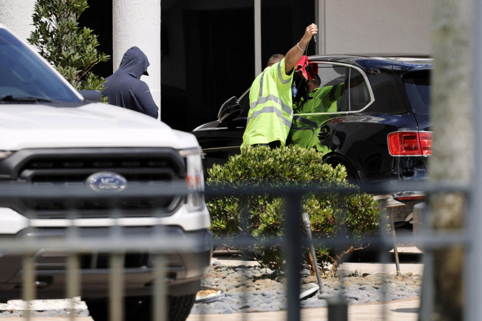 Workers attempt to gain access to a Bentley SUV in the driveway at Sean Kingston’s Southwest Ranches, Fla., home on Thursday, May 23, 2024. A SWAT team raided rapper Kingston’s rented mansion on Thursday, and arrested his mother on fraud and theft charges that an attorney says stems partly from the installation of a massive TV at the home. Broward County detectives arrested Janice Turner, 61, at the home. (Amy Beth Bennett/South Florida Sun-Sentinel via AP)