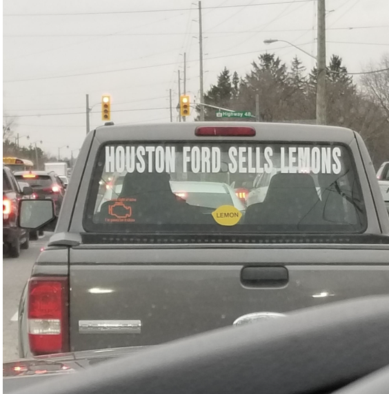 Sign in back window of car: "Houston Ford Sells Lemons"