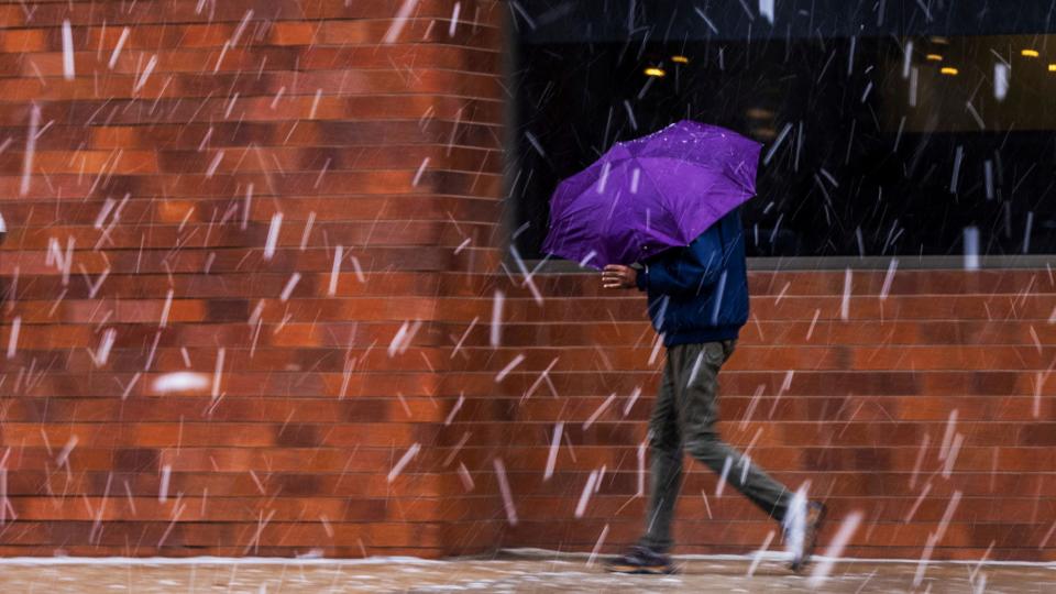 A pedestrian uses an umbrella to shield themself from the snow in downtown Omaha on Thursday, March 16, 2023.