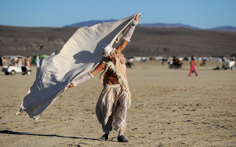 In this Sept. 2, 2010 photo, Jeffery Bale, of Portland, Oregon, uses a scarf to play with the wind at the annual Burning Man counterculture art festival, in the Black Rock Desert of Nevada. It's never been so hard to be a hippie. A quarter century after the free spirits moved their party from San Francisco's Baker Beach to a dried up ancient lake bed 110 miles north of Reno, the Burning Man counterculture festival is faced with turning large numbers of its longtime participants away. With its drum circles and decorated art cars, guerilla theatrics and colorful theme camps, the annual pilgrimage to the playa in the name of both everything and nothing has become just too darn popular for its own good. (AP Photo/Reno Gazette-Journal, Andy Barron)