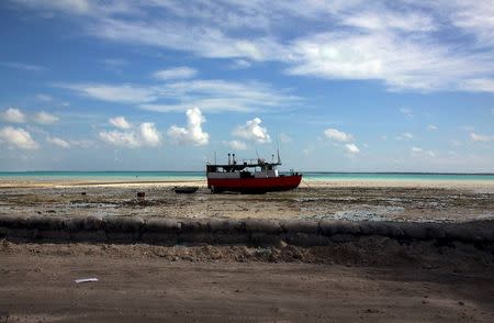 A boat sits on a reef-mud flat close to a lagoon at South Tarawa in the central Pacific island nation of Kiribati in this May 23, 2013 file photo. REUTERS/David Gray/Files