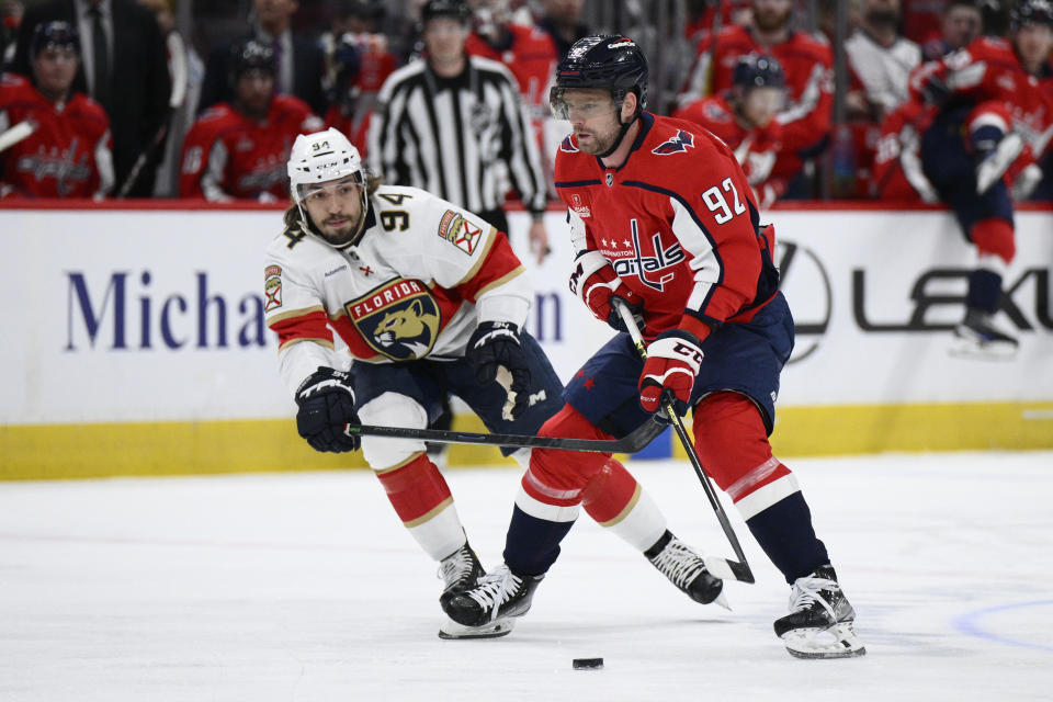 Washington Capitals center Evgeny Kuznetsov (92) and Florida Panthers left wing Ryan Lomberg (94) chase the puck during the first period of an NHL hockey game, Saturday, April 8, 2023, in Washington. (AP Photo/Nick Wass)