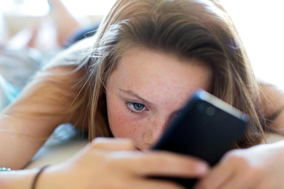Young person lying down and looking at a smartphone screen
