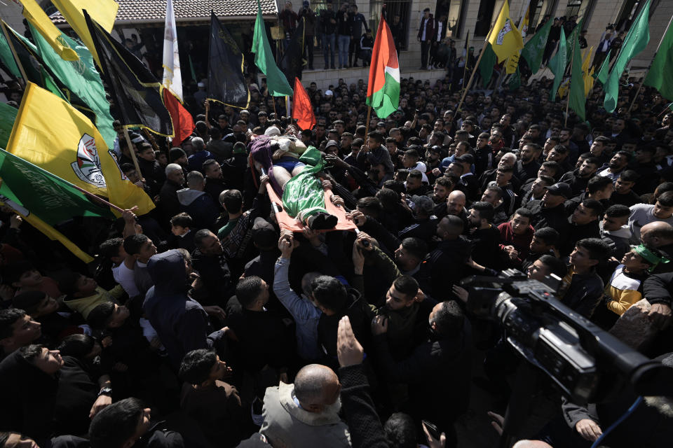 Palestinian mourners carry the body of Ahmed Daraghmeh, draped in the Hamas flag, during his funeral in the West Bank city of Nablus, Thursday, Dec. 22, 2022. Palestinian medics say Israeli forces have shot dead the 23-year-old man and wounded several others during clashes in the occupied West Bank. Daraghmeh was mortally wounded early Thursday when Palestinian militants exchanged fire with Israeli troops that entered the city of Nablus to escort Jewish worshippers to a site known as the biblical Joseph's Tomb in the Palestinian city. (AP Photo/Majdi Mohammed)