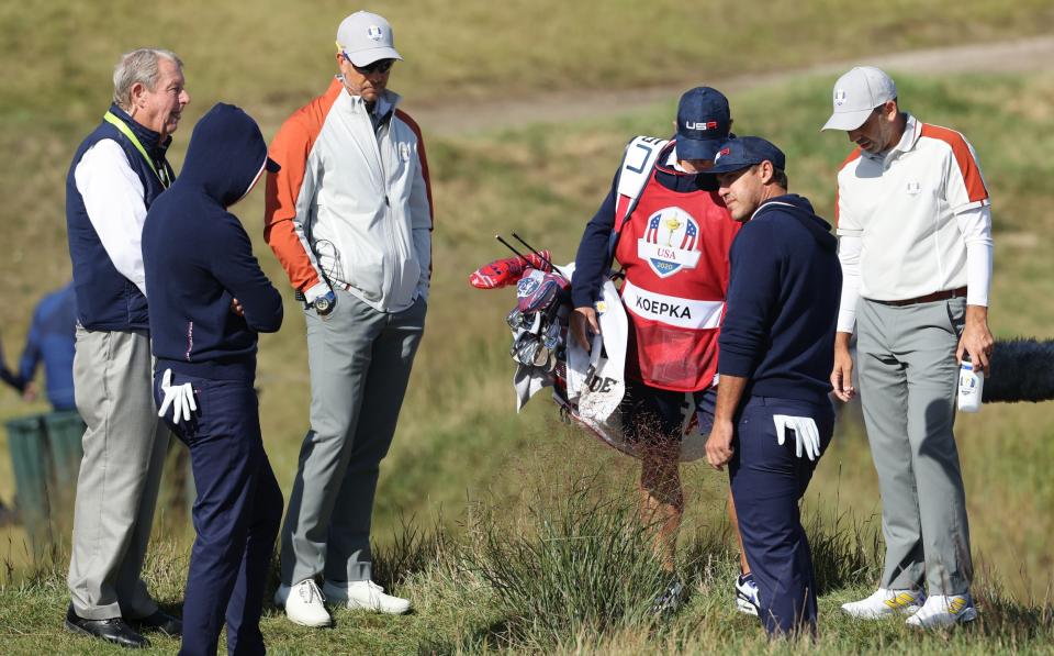 A rules lawyer inspects the lie of a ball for Daniel Berger and Brooks Koepka on the 15th hole - Getty Images