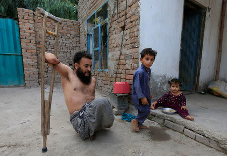 Khushhal Khan Ayobi 34, disable Afghan National Army (ANA) soldier walks with his children at his house in Jalalabad province, Afghanistan. August 2, 2017. REUTERS/Parwiz