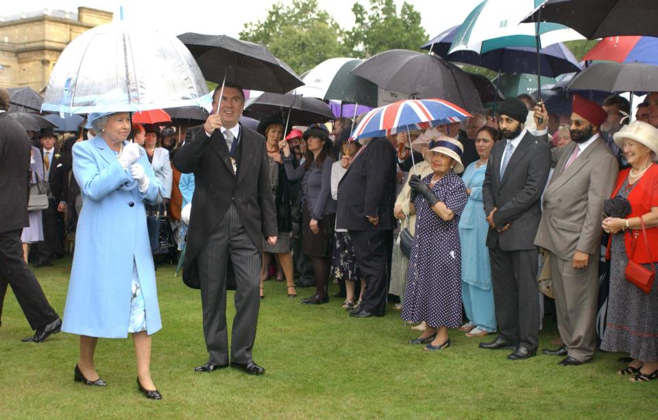 Queen Elizabth II is undaunted by heavy rain during a garden party for the Royal Society of Arts in the gardens of Buckingham Palace, London. Heavy storms have battered Britain over the last two days with thousands of people losing their electricity supplies.   (Photo by Fiona Hanson - PA Images/PA Images via Getty Images)