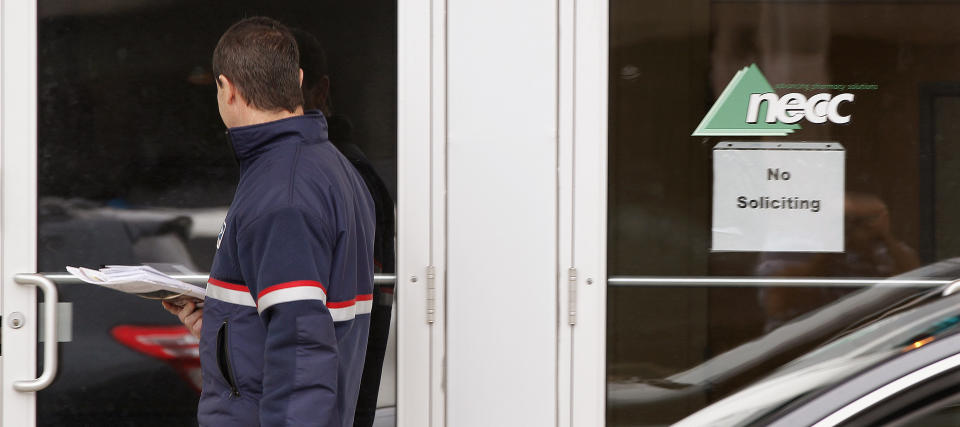 FILE - In a Thursday, Oct. 4, 2012 file photo, a delivery man walks up to the door of New England Compounding in Framingham, Mass. Federal and state investigators have been tightlipped about any problems they may have seen at the pharmacy whose steroid medication has been linked to a lethal outbreak of a rare fungal form of meningitis, or whether they have pinpointed the source of the contamination. They did disclose Thursday, Oct. 11, 2012 that they found fungus in more than 50 vials from the company. (AP Photo/Stephan Savoia, File)