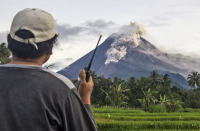 A volunteer uses his walkie talkie as he monitors Mount Merapi during an eruption in Sleman, Wednesday, Jan. 27, 2021. Indonesia's most active volcano erupted Wednesday with a river of lava and searing gas clouds flowing 1,500 meters (4,900 feet) down its slopes. (AP Photo/Slamet Riyadi)