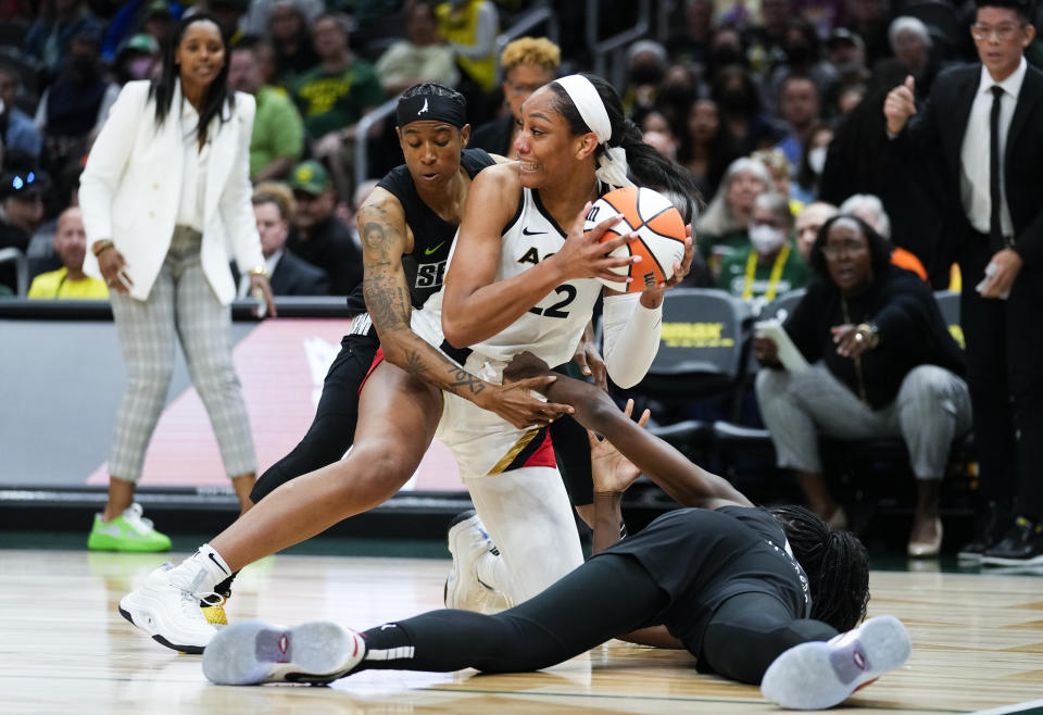 Las Vegas Aces forward A'ja Wilson (22) looks to pass the ball away during a scrum with Seattle Storm guard Yvonne Turner, left, and center Ezi Magbegor, right, during the first half of a WNBA basketball game Saturday, May 20, 2023, in Seattle. (AP Photo/Lindsey Wasson)