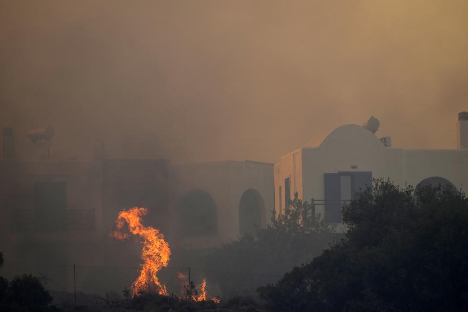 A wildfire burns in Gennadi village, on the Aegean Sea island of Rhodes, southeastern Greece, on Tuesday, July 25, 2023. A firefighting plane has crashed in southern Greece, killing both crew members, as authorities are battling fires across the country amid a return of heat wave temperatures. (AP Photo/Petros Giannakouris)