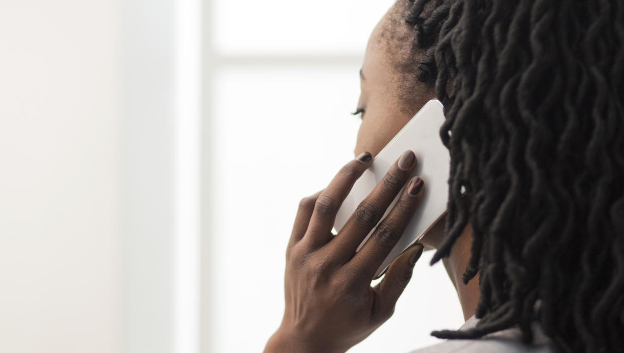 Unrecognizable African American woman Talking On Cellphone Looking Out Of The Window In Office. Closeup, Copy Space