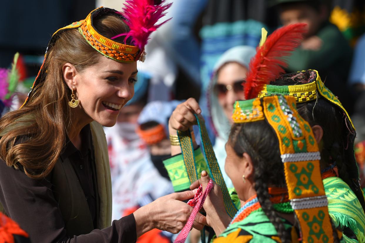 TOPSHOT - Britain's Catherine (L), Duchess of Cambridge, receives gifts from a member of the Kalash tribe during her visit to the Bumburate Valley in Pakistan northern Chitral District on October 16, 2019. - Prince William and his wife Kate flew near the Afghan border to visit a remote Hindu Kush glacier on October 16, after a morning spent trying on feathered traditional caps and luxurious shawls in Pakistan's mountainous north. (Photo by FAROOQ NAEEM / AFP) (Photo by FAROOQ NAEEM/AFP via Getty Images)