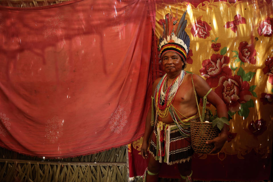 Tenetehara Indigenous Shaman Paulo Sergio Tembe, 50, poses for photo in his home with the basket of roots of traditional medicine, in the Alto Rio Guama Indigenous Territory, where they have enforced six months of isolation during the COVID-19 pandemic, near the city of Paragominas, state of Para, northern region of Brazil, Monday, Sept. 7, 2020. The Shaman says that the strength of traditional medicine and the Indigenous way of life protected the lands of the Tembe from the pandemic. The Indigenous group, also known as Tembe, held a festival this week to celebrate and give thanks that none of their members have fallen ill with COVID-19, after closing their area off in March. (AP Photo/Eraldo Peres)