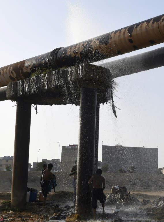 Karachi youngsters cool off under a leaking water pipeline