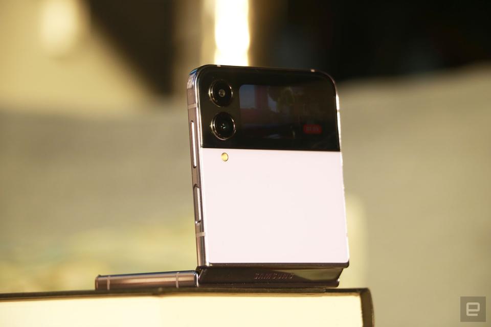 The Galaxy Z Flip 4 half folded and propped up on a book with its cover display facing out and showing the image of something being recorded.