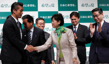 Tokyo Governor Yuriko Koike (C), the leader of her new Party of Hope, shakes hands with her party member Goshi Hosono (L), a former environment minister as Masaru Wakasa (R), a former prosecutor who left the ruling Liberal Democratic Party claps his hands during a news conference to announce the party's campaign platform in Tokyo, Japan, September 27, 2017. REUTERS/Issei Kato