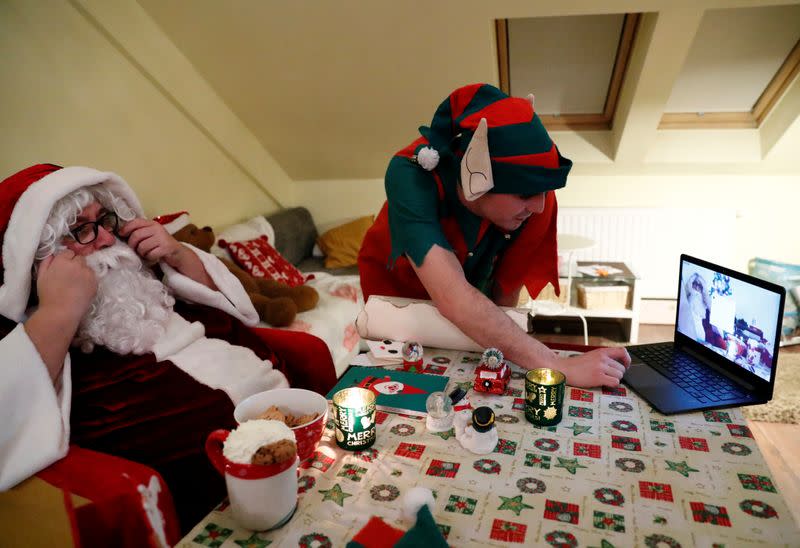 An assistant helps Pillmayer, dressed as Santa, as he prepares to interact with children by video, amid the COVID-19 outbreak in Budapest