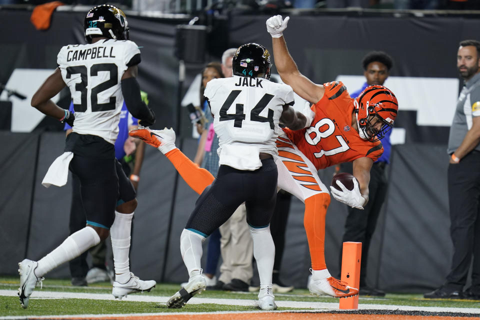 Cincinnati Bengals' C.J. Uzomah (87) goes in for a touchdown against Jacksonville Jaguars' Myles Jack (44) and Tyson Campbell (32) during the second half of an NFL football game, Thursday, Sept. 30, 2021, in Cincinnati. (AP Photo/Michael Conroy)