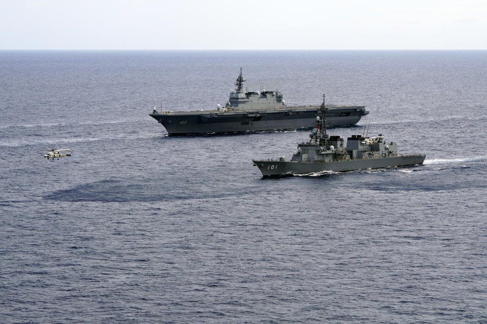 FILE - In this June 28, 2019, file photo, Japan's Maritime Self-Defense Force helicopter carrier Izumo (DDH-183) and destroyer JS Murasame (DD-101) participate in drills that included maritime navigation and emergency response exercises in Sulu Sea. Japan approved Friday, Dec. 20, 2019, a draft defense budget that included cost to develop own fighter jets to succeed the nation's aging warplanes and import some of F-35 stealth fighters as components for assembly at home rather than importing the expensive American warplanes as finished products to reduce costs and acquire expertise. To accommodate the F-35Bs, the Defense Ministry will spend 3.1 billion yen ($290 million) to reconfigure one of its two helicopter carriers, Izumo, with a heat-resistant flight deck and guiding lights, beginning next year. (AP Photo/Emily Wang, File)