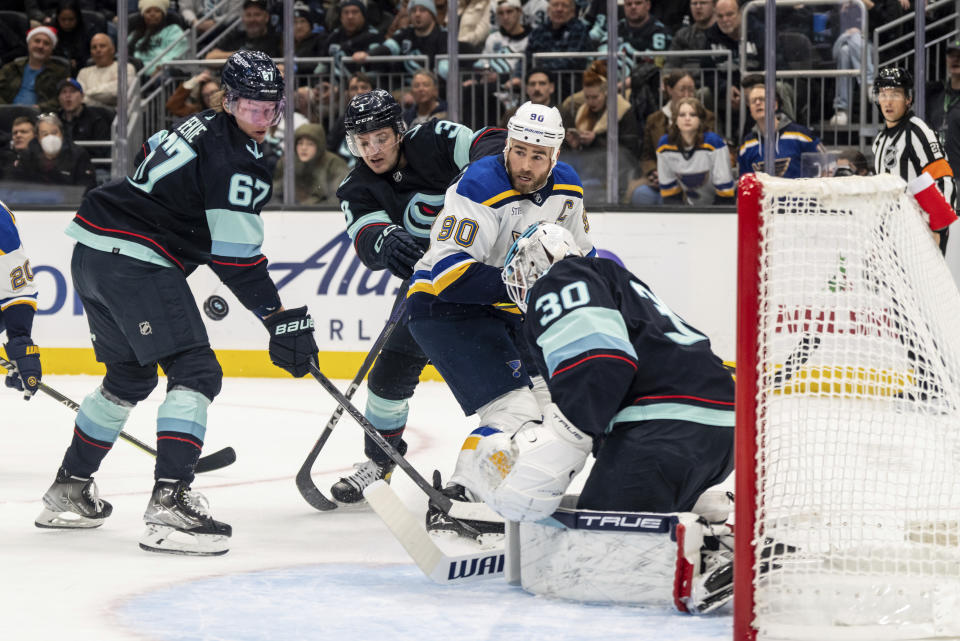 Seattle Kraken forward Morgan Geekie, left, defenseman Will Borgen, second from left, and goalie Martin Jones, right, and St. Louis Blues forward Ryan O'Reilly attempt to get to the puck in front of the goal during the first period of an NHL hockey game Tuesday, Dec. 20, 2022, in Seattle. (AP Photo/Stephen Brashear)