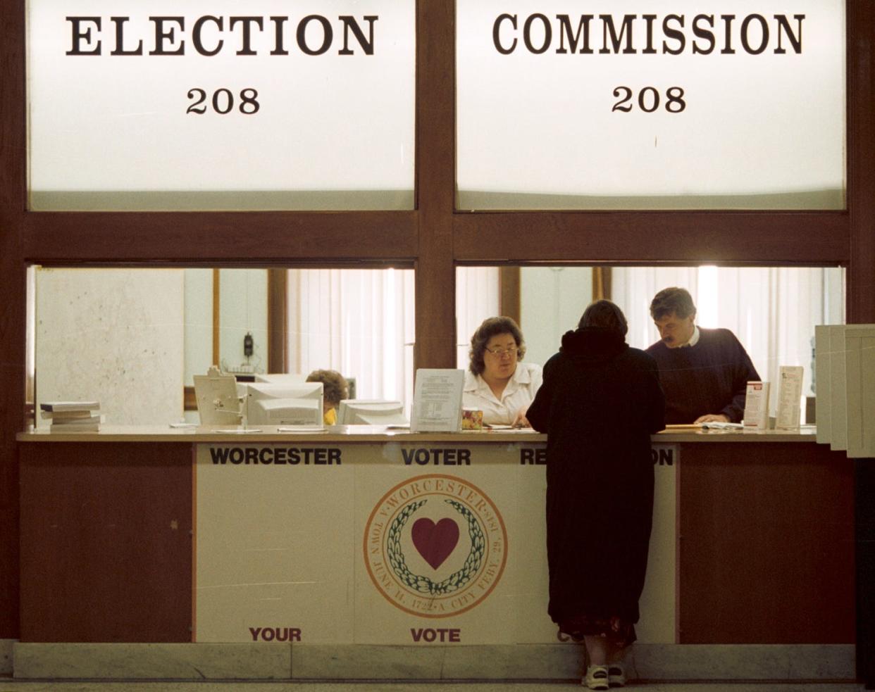 In a file photo, a voter talks with clerks at the Worcester Election Commission office in City Hall.