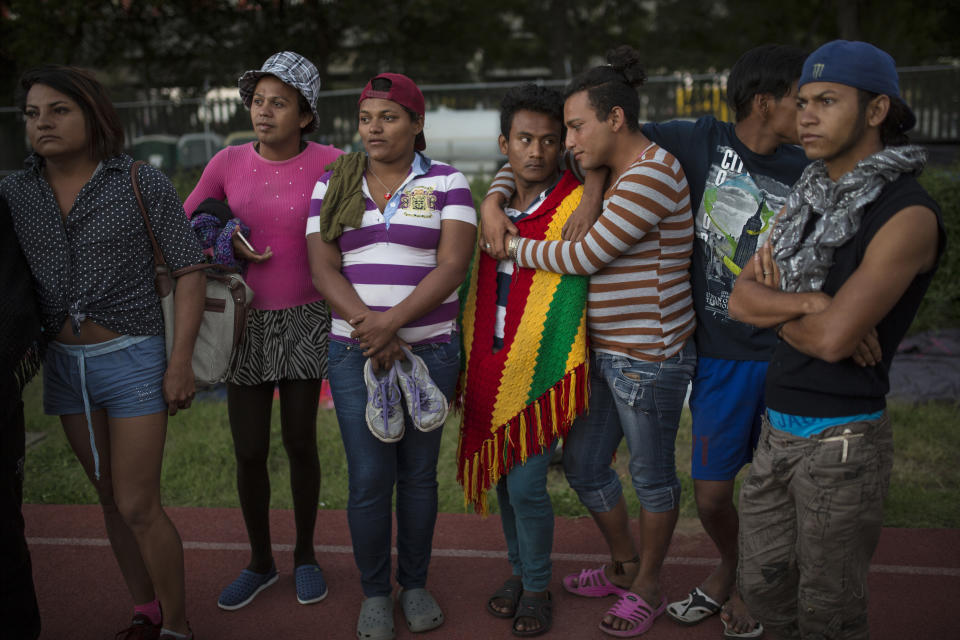 In this Nov. 4, 2018 photo, members of a group of 50 or so LGBTQ migrants, stand on the race track at the Jesus Martinez stadium that was turned into a makeshift shelter, in Mexico City. Fleeing violence and discrimination back home because of their gender identity or sexual orientation, the LGBTQ migrants have found the journey north to be just as threatening and have banded together for protection against mistreatment from their fellow travelers. (AP Photo/Rodrigo Abd)