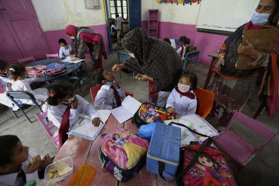 A health worker administers a polio vaccine to a child at a school in Lahore, Pakistan, Monday, Aug. 2, 2021. The government launched polio vaccination drives across Pakistan in hopes to eradicate the crippling disease by the end of the year. (AP Photo/K.M. Chaudhry)