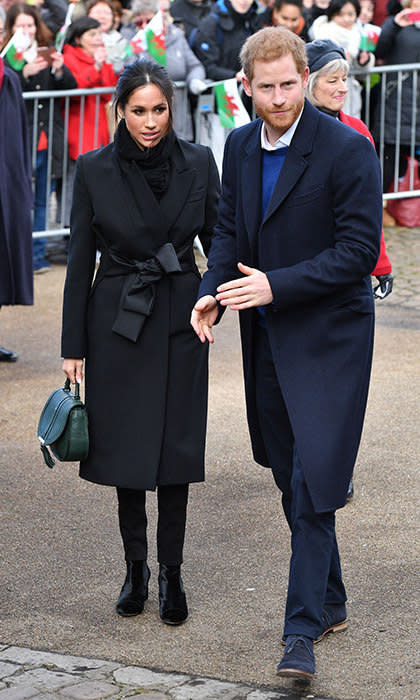 Meghan Markle and Prince Harry, all in many shades of dark navy blue, stand next to each other