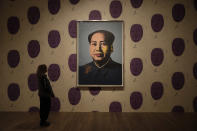 A Tate representative poses for photographs next to the Andy Warhol pieces 1972 "Mao" acrylic paint and screenprint on canvas, displayed on 1974, reprinted 1994 "Mao Wallpaper" during a media preview for the exhibition "Andy Warhol" at the Tate Modern gallery in London, Tuesday, March 10, 2020. The exhibition, which runs from March 12 to September 6, features over 100 works spanning the American artist's career in the second half of the 20th century until his death in 1987. (AP Photo/Matt Dunham)