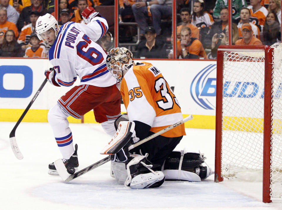 Philadelphia Flyers' Steve Mason, right, stops the puck with his stick as New York Rangers' Benoit Pouliot, left, looks back for it during the second period in Game 4 of an NHL hockey first-round playoff series on Friday, April 25, 2014, in Philadelphia. (AP Photo/Chris Szagola)