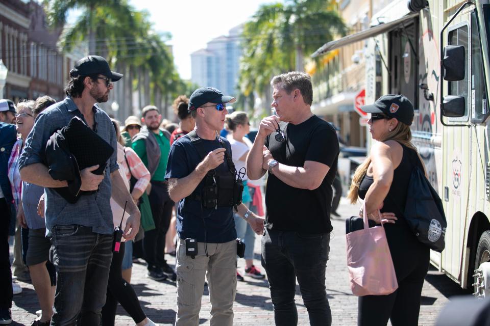 Tyler Florence, second from right, talks to a crew member for his show, "The Great Food Truck Race” while filming in downtown Fort Myers on Wednesday, Feb. 21, 2024.