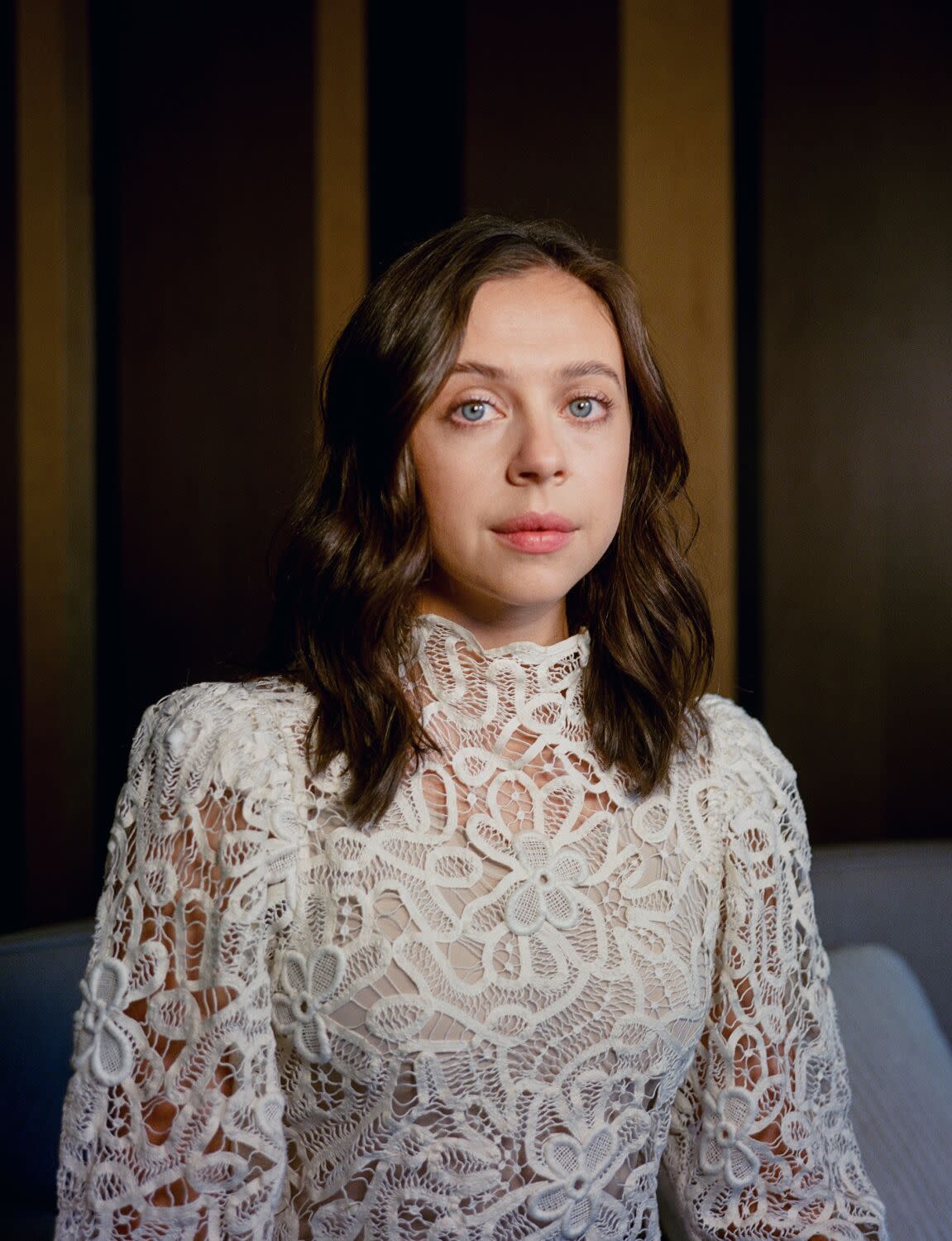 Bel Powley is photographed on a balcony with the New York City skyline in the background.