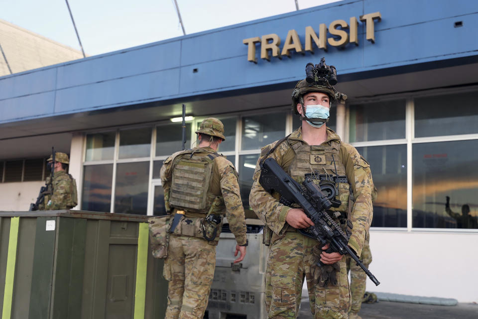 Australian soldiers stand outside the airport in Honiara, Solomon Islands, Saturday, Nov. 27, 2021. Violence receded in the capital of the Solomon Islands, but the government showed no signs of attempting to address the underlying grievances that sparked two days of riots, including concerns of the country's increasing links with China. (Gary Ramage via AP)